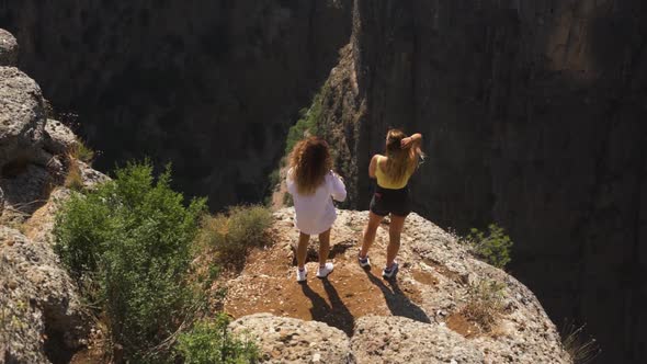Friends Stand on Rock Looking at Gap Between Old Mountains