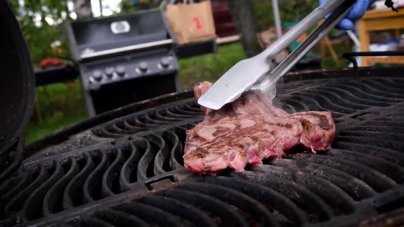 Juicy fried steak is turned over on a hot grill