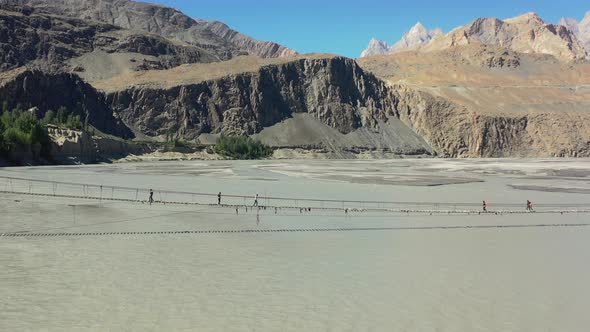 aerial drone flying backwards revealing the Passu Cones mountains in the distance as tourists cautio