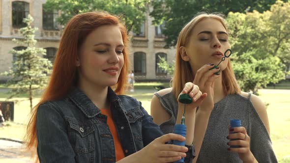Two Girls Blowing Bubbles Outdoors
