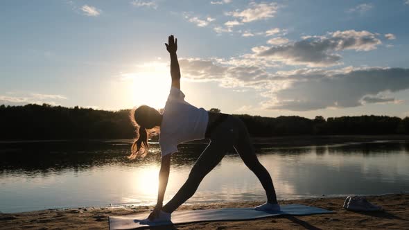 Woman Doing Sports Exercises at Beautiful Sunset on the Beach, Sun Glare From the Water