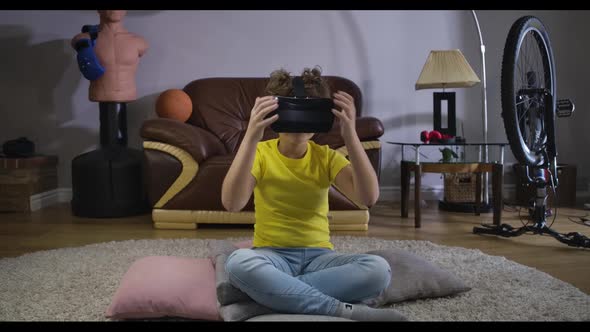 Portrait of Teenage Caucasian Boy in VR Headset Sitting on the Floor at Home and Looking Around