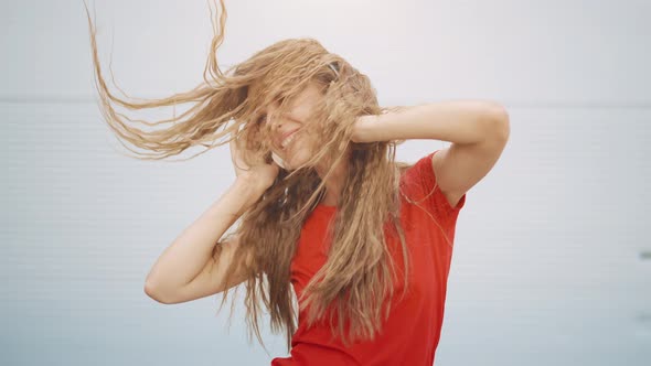 A Young Girl in Headphones is Listening to Music and Amusingly Dancing on a Light Background