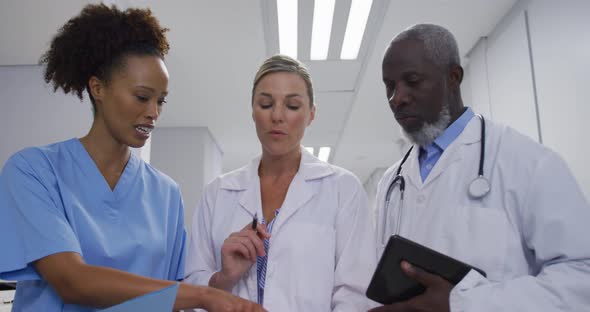 Diverse doctors and medical workers standing in hospital corridor and talking