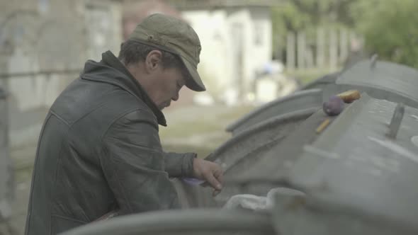 A Beggar Homeless Man Tramp Is Looking for Food in a Trash Can. Kyiv. Ukraine