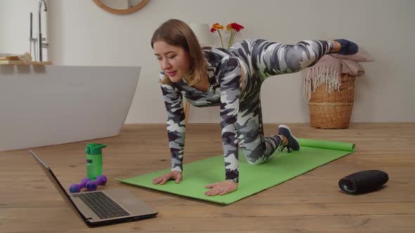 Pretty Motivated Sporty Fitness Female Practicing Yoga Online Class with Laptop in Domestic Room