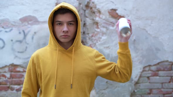 guy shakes spray paint on the background of the old wall