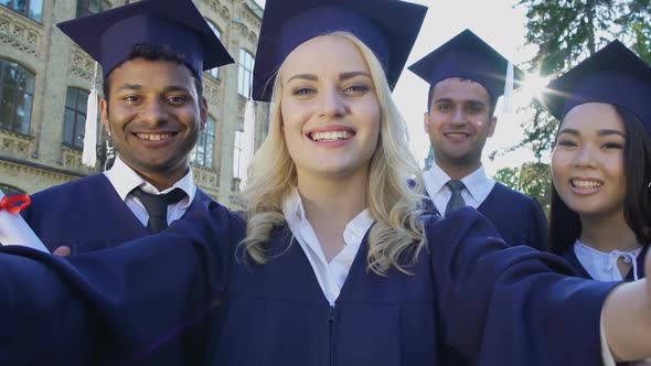 Classmates in Academic Regalia Taking Selfie on Graduation Day, Achievement