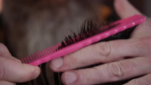 Barber Combs the Client's Hair with a Comb and Makes a Haircut with Scissors