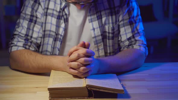 Close Up Man Sits at a Table and Reads a Prayer