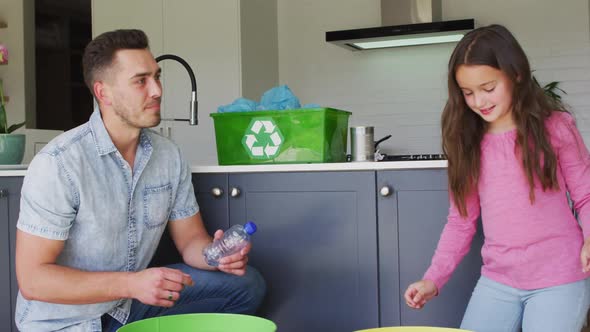 Happy caucasian father and daughter segregating rubbish in kitchen