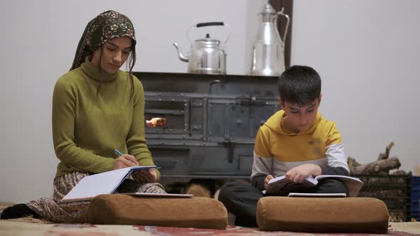 Two Sibling Studying in Front of the Stove