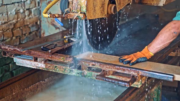 Automated circular saw cuts the stone slab at industrial factory.