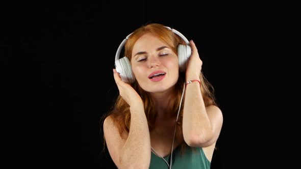 Girl Listens To Her Favorite Music Through Headphones. Black Background