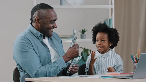 African American Father Helps to Do Homework Teaches Little Daughter Arithmetic Using Dollar Bills