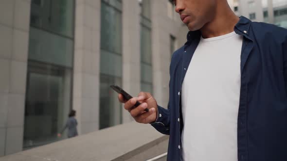 Ethnic Man Using Smartphone on Street