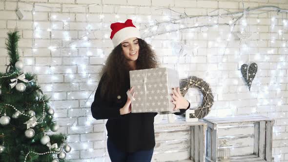 Gift Box New Year Day Celebration. Young attractive woman with gift box near fireplace