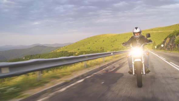 Front Shot of Biker with Open Helm Riding Motorcycle on Asphalt Road With Rural