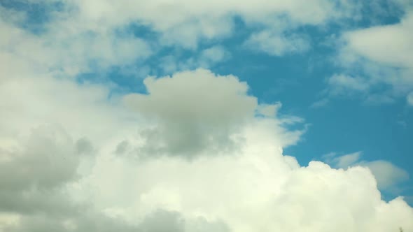 White clouds fly across a bright blue sky