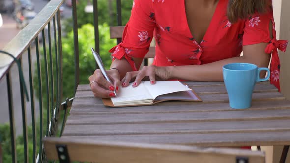 A woman writing in a journal diary traveling in a luxury resort town in Italy, Europe