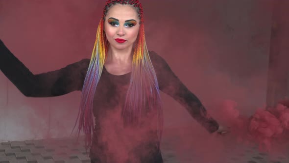A Girl in a Simple Black Dress with Colored Braids and Rainbow Makeup Posing in Red Thick Smoke in a