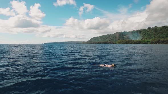 Aerial View on Woman Snorkeling on Surface of Tropical Sea Under Beautiful Sky