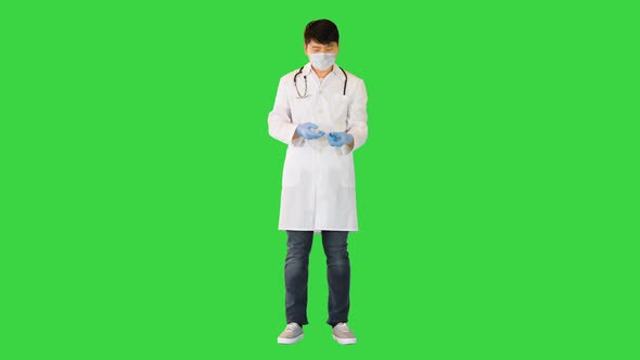 Young Asian Doctor is Getting Solution From an Ampule with a Syringe on a Green Screen Chroma Key