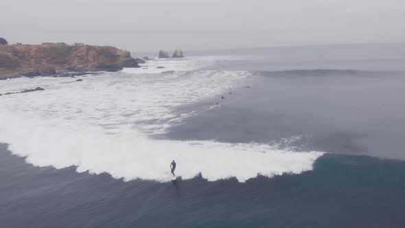 Aerial shot following Surfer riding a wave at Punta de Lobos, Chile-4k