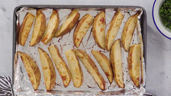 Flat lay. Freshly baked potato wedges with spices on a white serving tray.