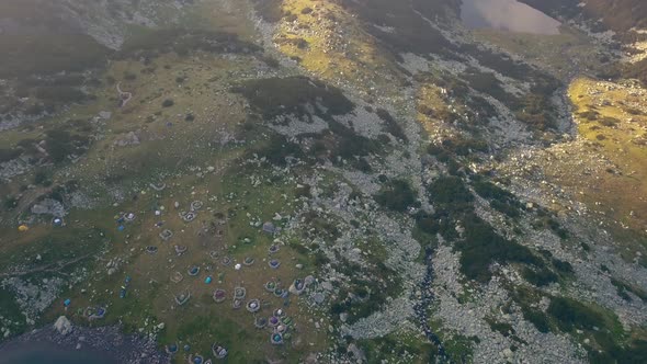 Wide aerial drone slowly tilting up from camping group on top of a mountain.  Shot ends on full moun