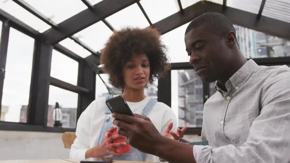 African man and mixed race woman using smartphone