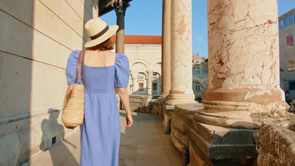 A young girl in a blue dress walking in the old building