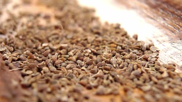 Dry anise seeds falling on a wooden surface of rustic bowl in slow motion . Aniseed dried spice