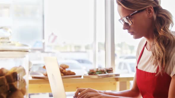 Thoughtful waitress using laptop