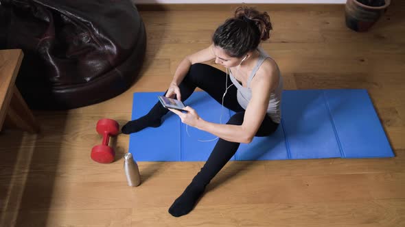 Smiling sportswoman using smartphone at home