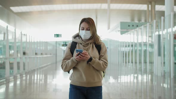 Tourist in Medical Mask Using Smart Phone with a Backpack on Back Walking in the Area of the