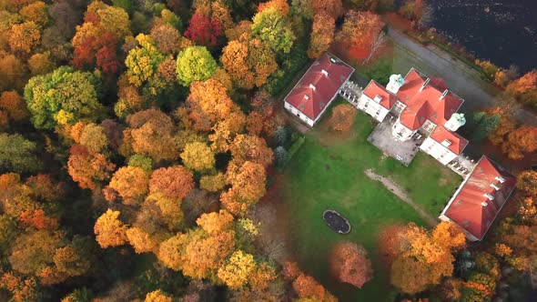 Flying over the beautiful Castle in autumn Forest. Located in landscape park with green trees forest