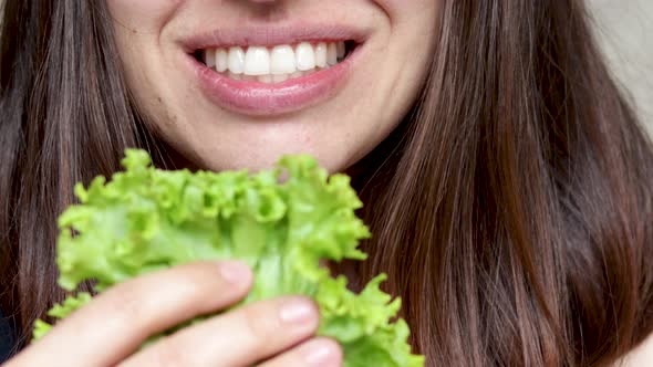 pretty happy woman girl holding salad leaf lettuce in front on face and smiles. healthy foo