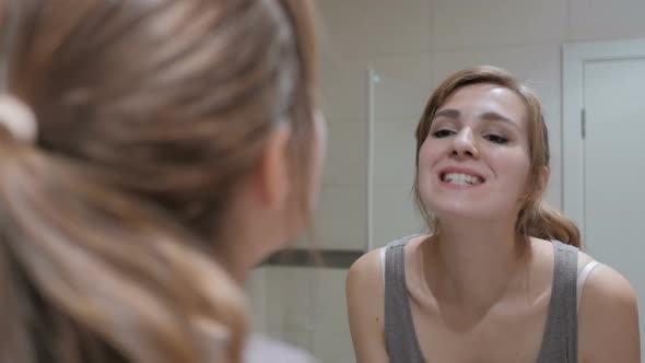 Young Woman Checking Her Teeth in Mirror