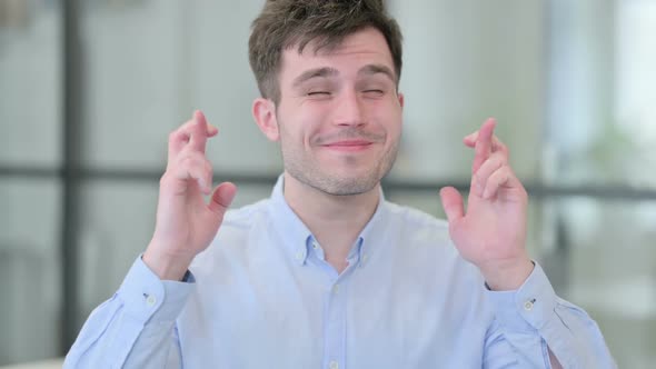 Young Man Praying with Fingers Crossed