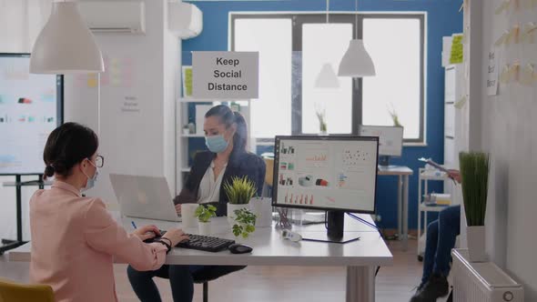 Business Team Typing Financial Strategy on Laptop Wearing Face Mask to Prevent Infection with