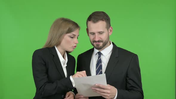 Professional Male and Female Studying Documents Against Chroma Key