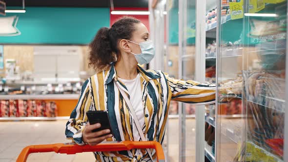 Attractive Brunette Woman Wearing Mask Chooses Seafood in the Supermarket
