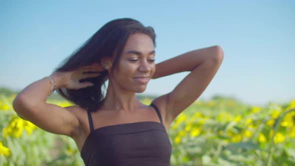 Charming Black Woman Relaxing in Sunflower Field