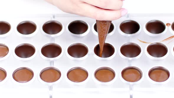 Chocolatier Pouring Caramel Filling Into Chocolate Mold Preparing Candy Slow Mo