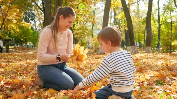 Video of Young Smiling Mother with Her Little Son Sitting on Grass at Autumn Park