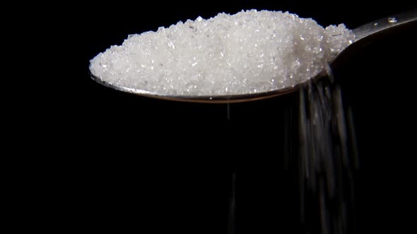 Closeup Macro of Pouring Full Spoon Crystals White Sugar .