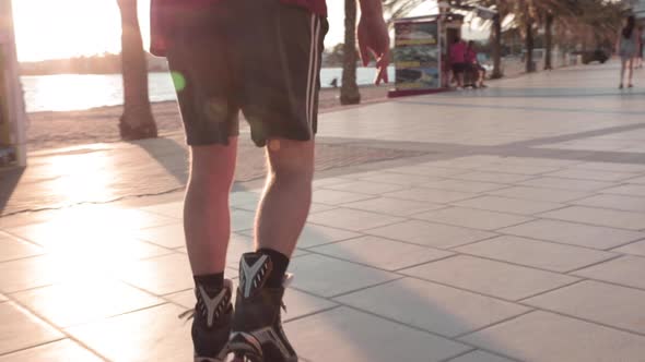 Slow motion,  on person's legs roller blading on pavement during golden hour. No face