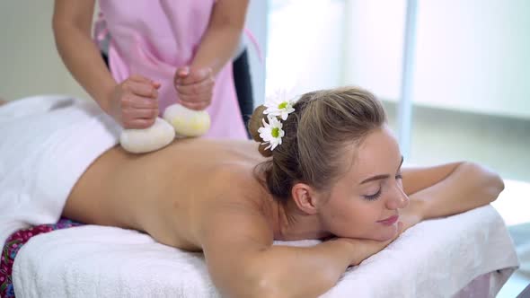 Massage Therapist Using Herbal Compress on Woman