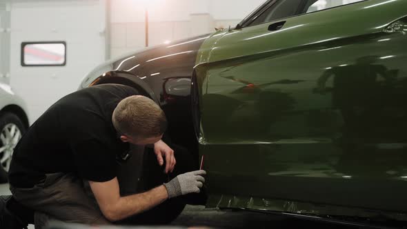 Mechanic Cutting Vinyl Car Wrap on a Car Door Vinyl Wrapping Process